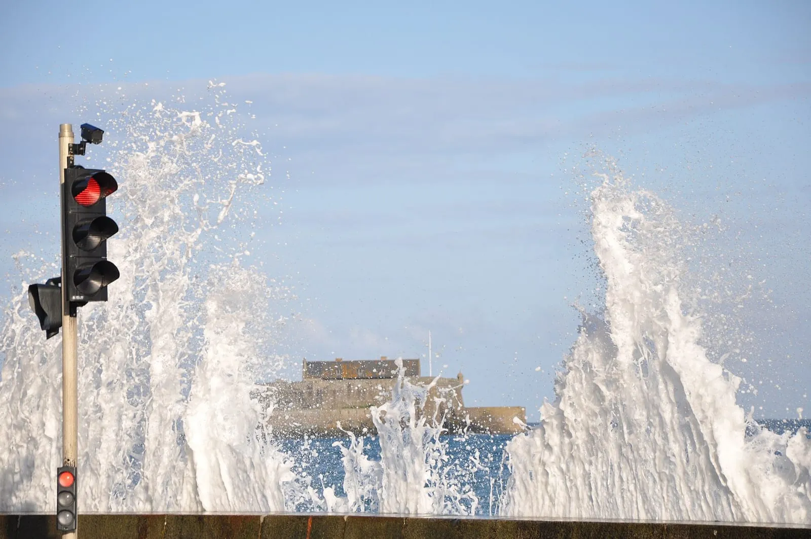 Spray rising above the seafront wall, Fort National behind
